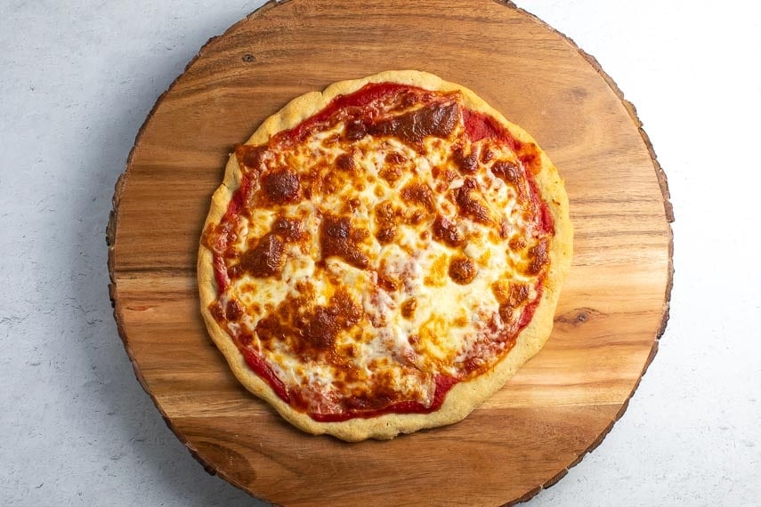 Low FODMAP Easy Pizza on round wooden board and light grey background