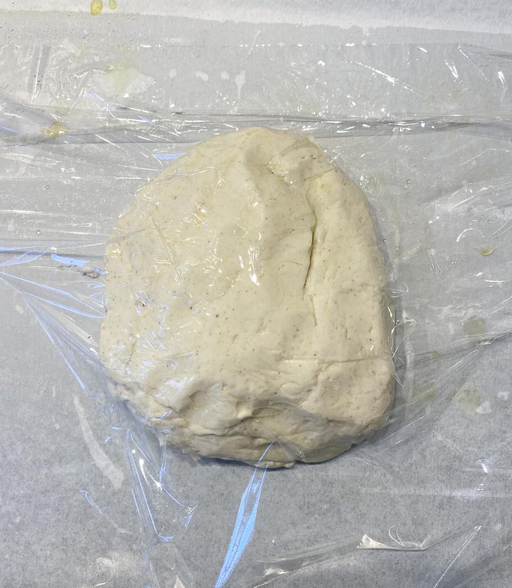 covering pizza dough with plastic before rising