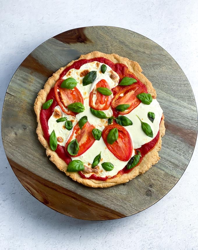 easy pizza with fresh mozarella, fresh tomatoes and fresh basil on round wooden platter