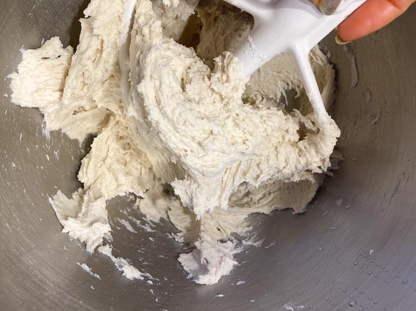 making pizza dough in stand mixer using flat paddle; you can see how it is mpoist, but coming away from the sides of the bowl