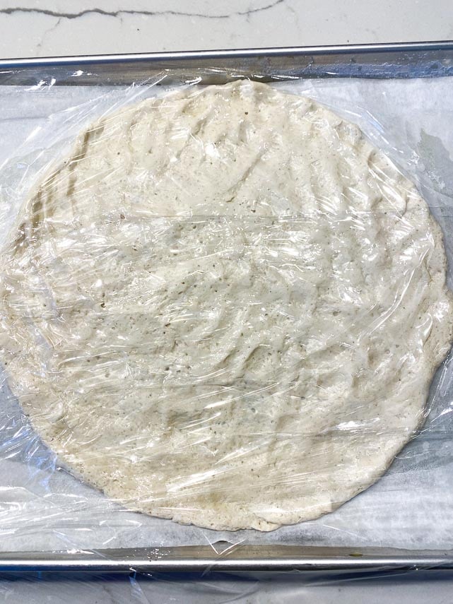 pizza dough, patted out on pan, covered with plastic wrap while oven preheats