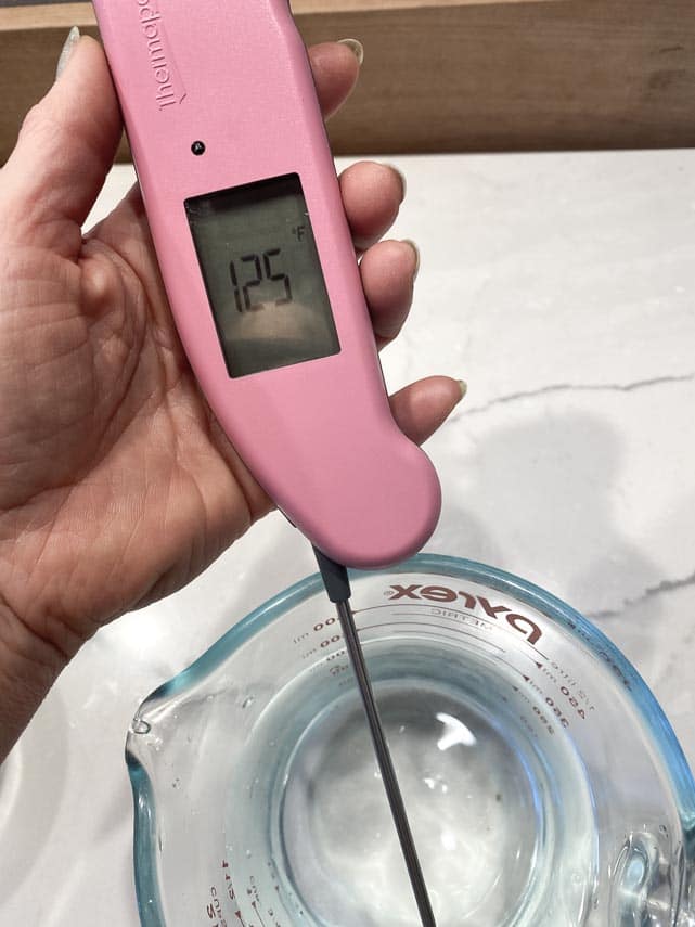 use a good instant read thermometer to assess water temperature' pink thermometer held in women's hand