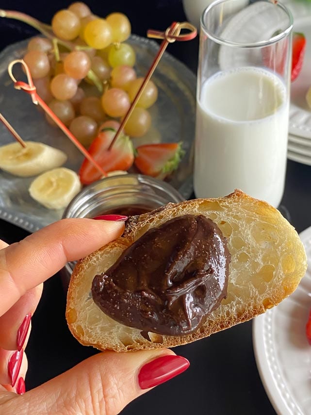 vertical image of homemade Nutella on bread held in hand
