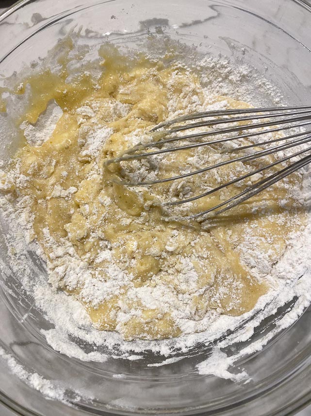 begin to combine dry and wet ingredients for banan bread in glass bowl with whisk