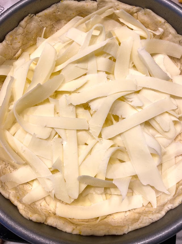 broad strips of mozarella on deep dish pizza before cooking