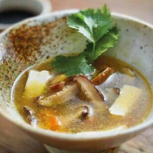 close up of tofu mushroom soup in rustic bowl