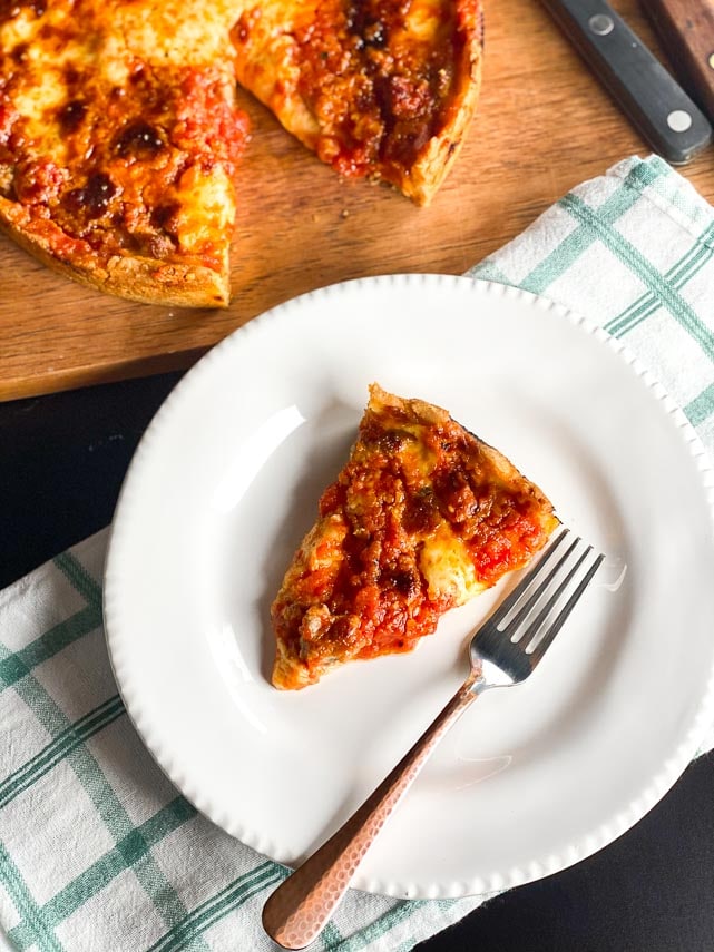 deep dish low FODMAP pizza on board wedge cut out; copper fork