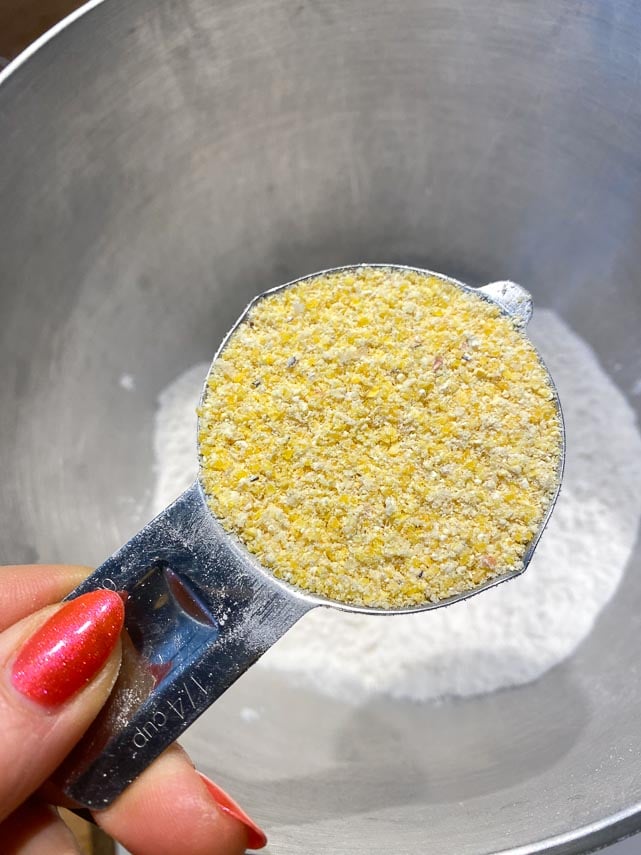 medium grind cornmeal in a measuring cup held over a bowl