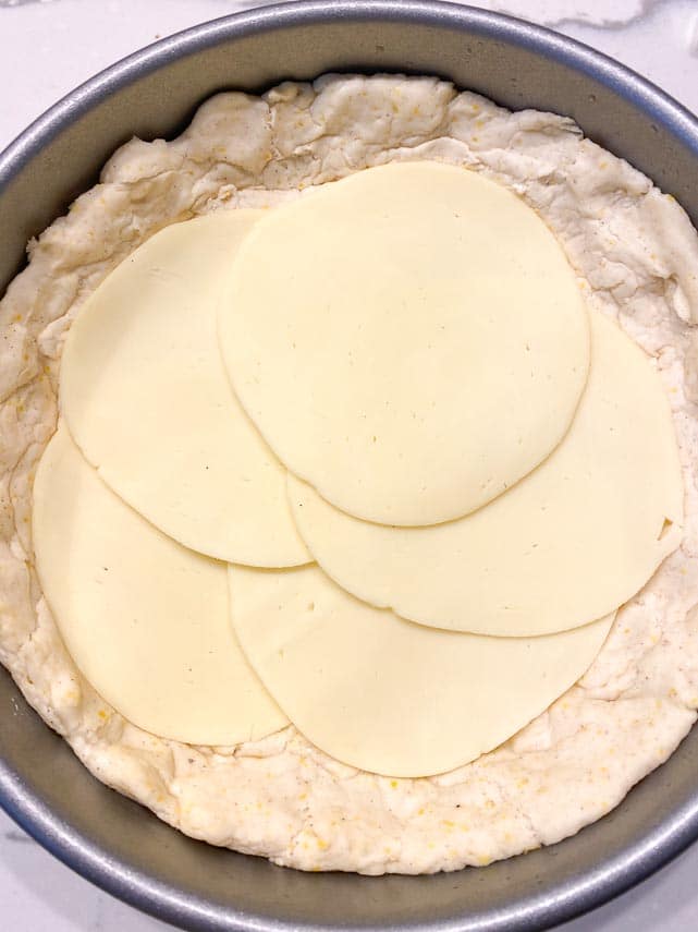 thin slices of Provolone on deep dish pizza before cooking