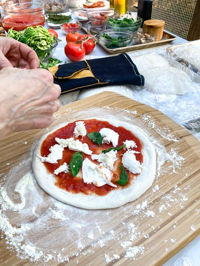 Adding sauce and toppings to Neapolitan pizza dough