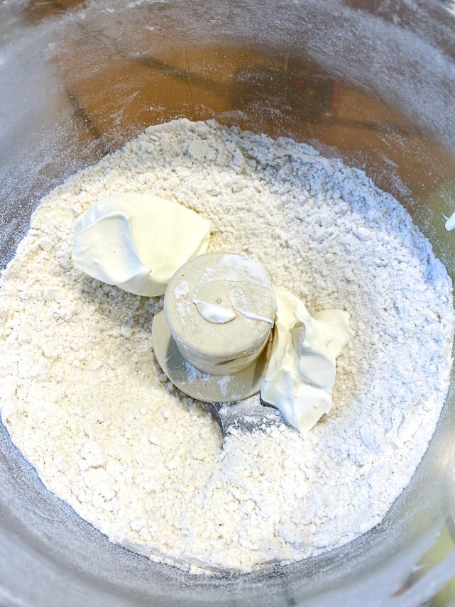 Cream cheese added to pie dough ingredients in food processor