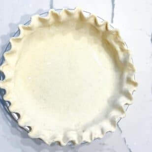 Cream cheese pie crust in pie plate, fluted edge on marble surface-2