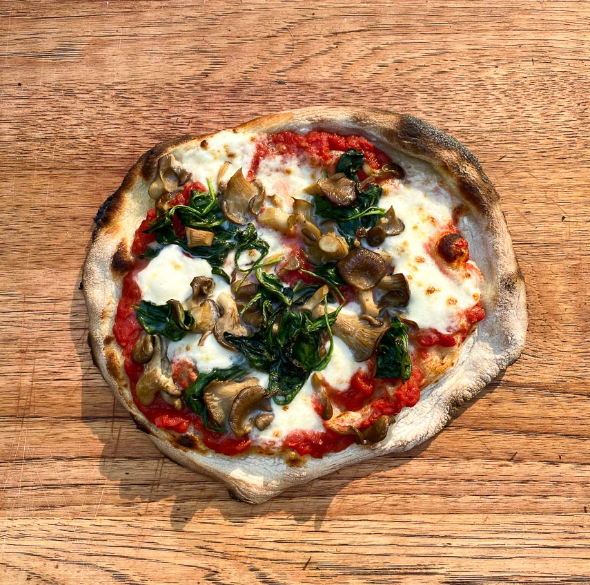 Spinach mushroom pizza on wooden board