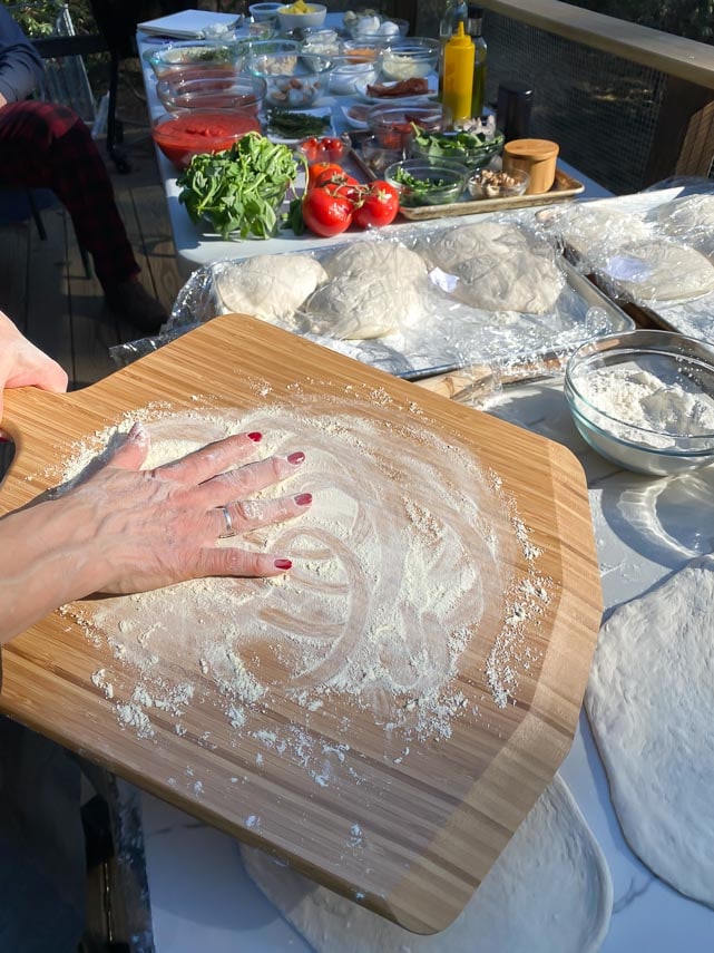 adding flour to wooden pizza peel