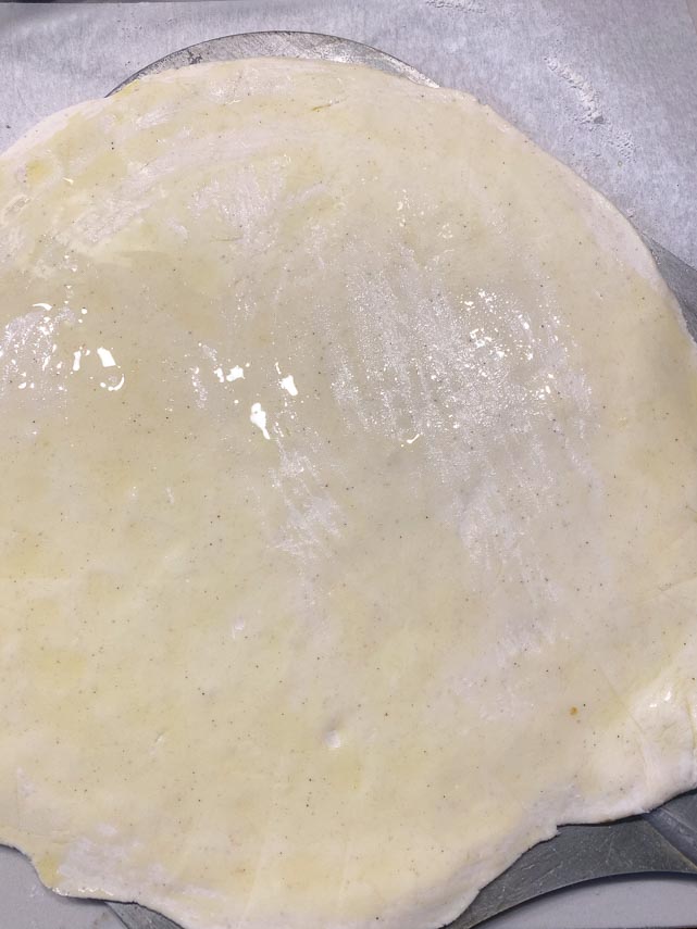 brushing Caputo GF pizza crust with olive oil before baking