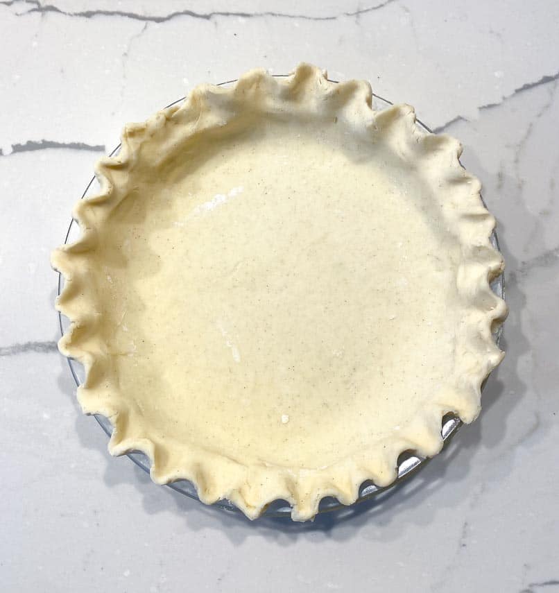 cream cheese pie crust in pie plate, fluted edge on marble surface