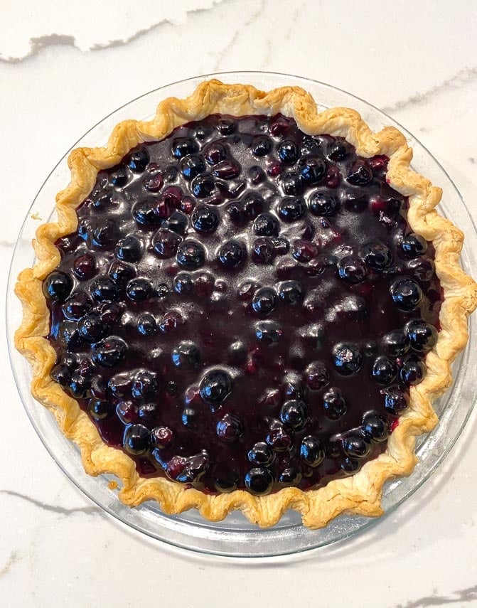 fresh blueberry pie on crust on marble surface