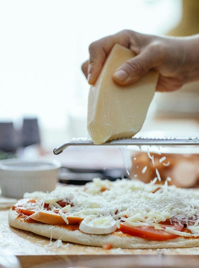 grating cheese over pizza by hand