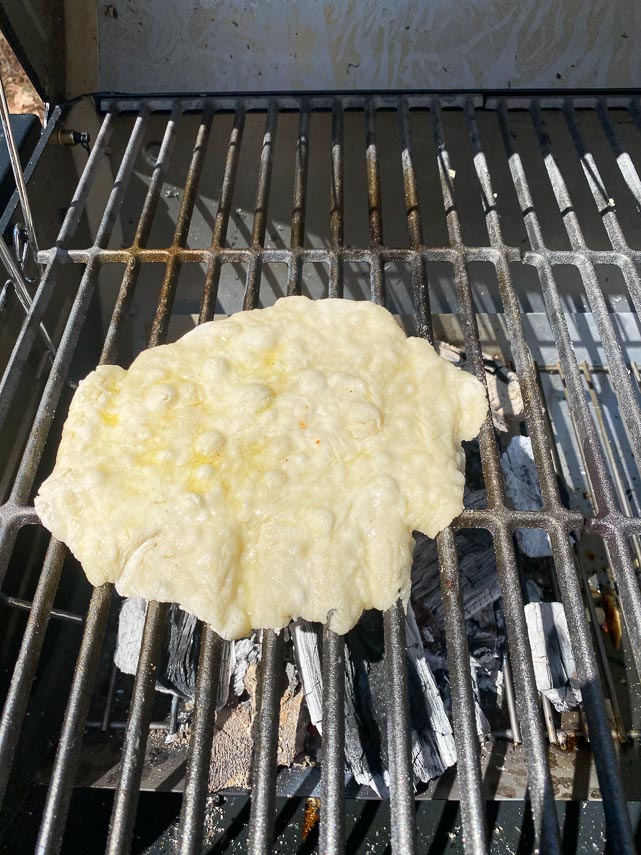 grilled pizza dough beginning to cook on first side
