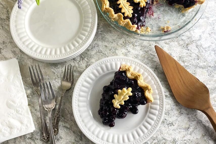 overhead image of low FODMAP Fresh Blueberry Pie on white gray quartz and white plate