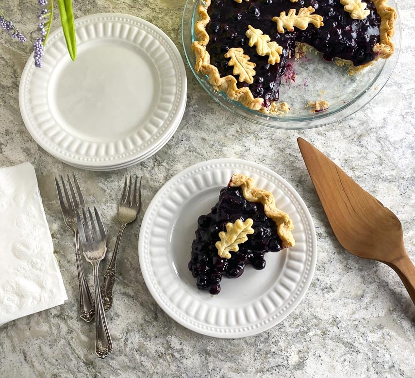 overhead image of low FODMAP Fresh Blueberry Pie on white gray quartz and white plate