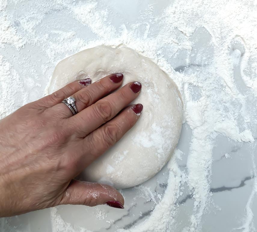 patting out pizza dough to preserve the cornicione-rim