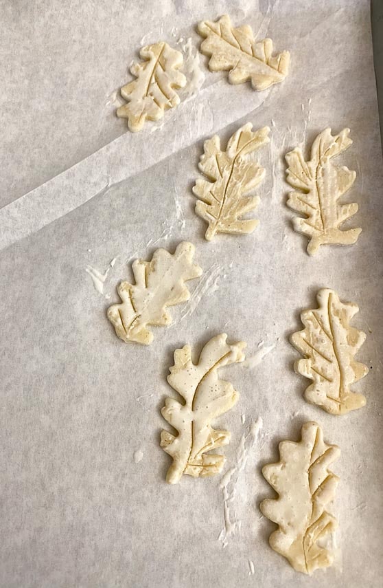 pie crust leaves cut out, on parchment lined pan, brushed with cream, before baking