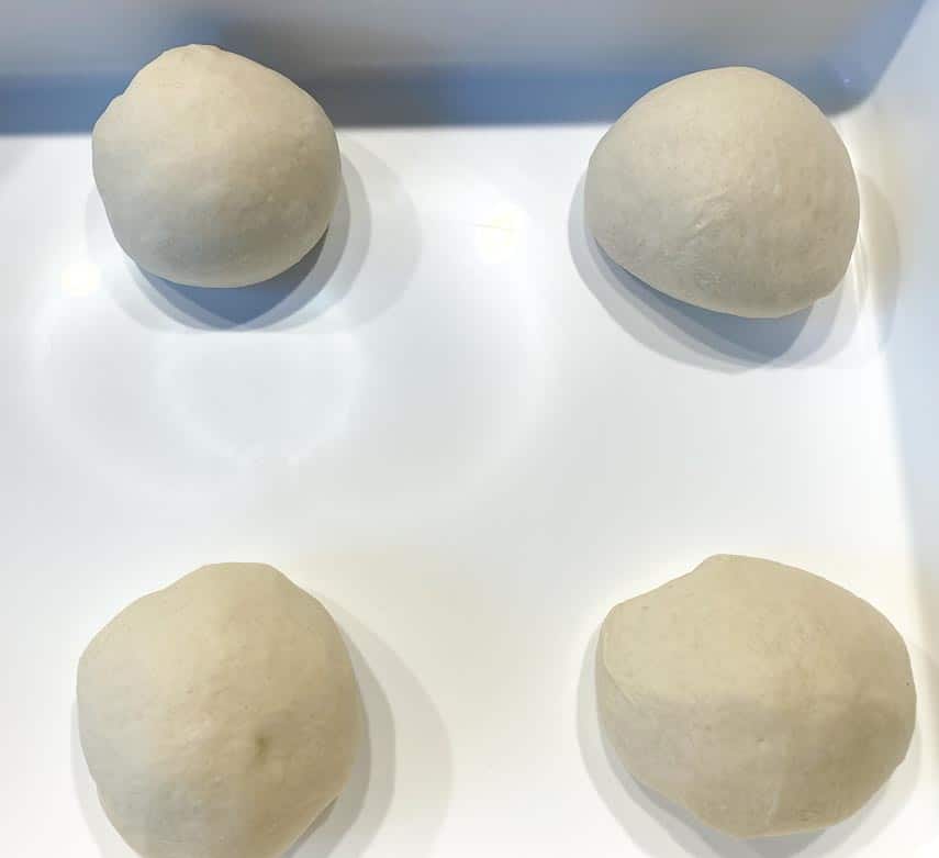 placing round dough balls of Neapolitan pizza dough in storage container