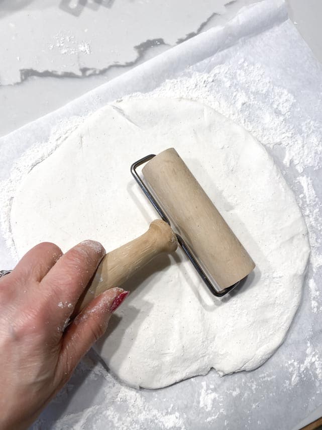 using a small hand roller to roll out Caputo GF pizza dough