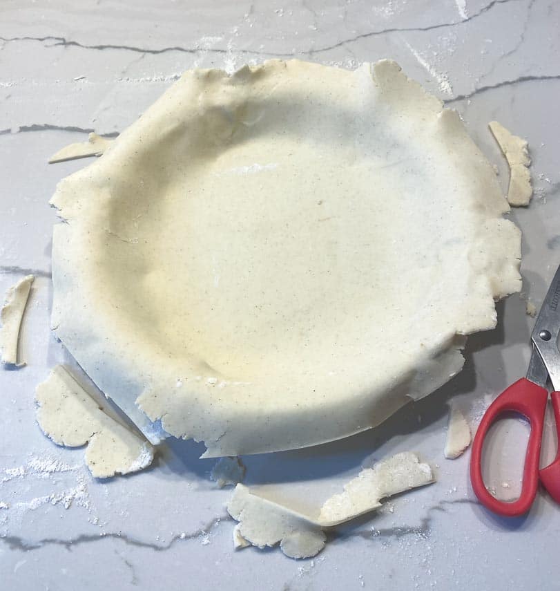 using scissors to trim pie dough