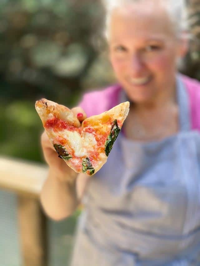 woman holding pizza toward camera