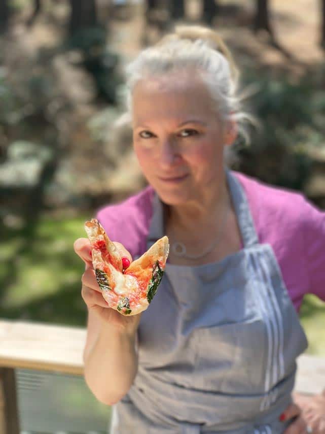 woman holding wedge of pizza directly at camera