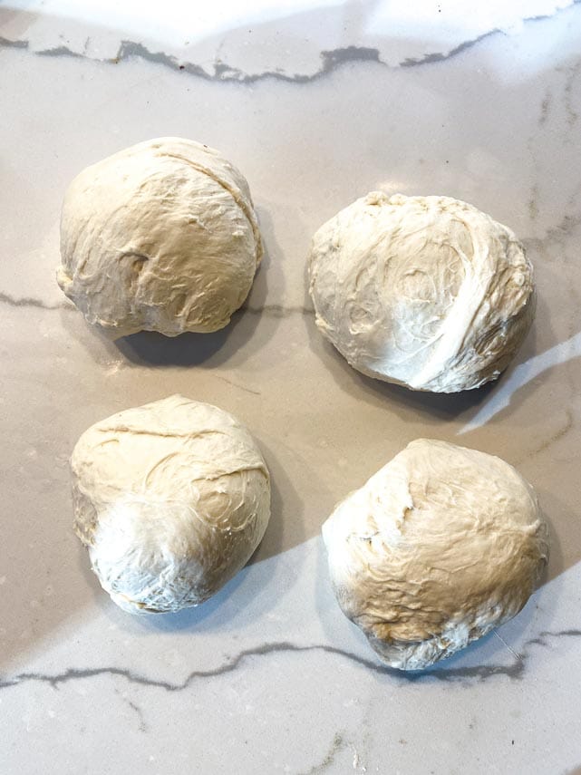 4 balls of sourdough pizza dough on marble surface