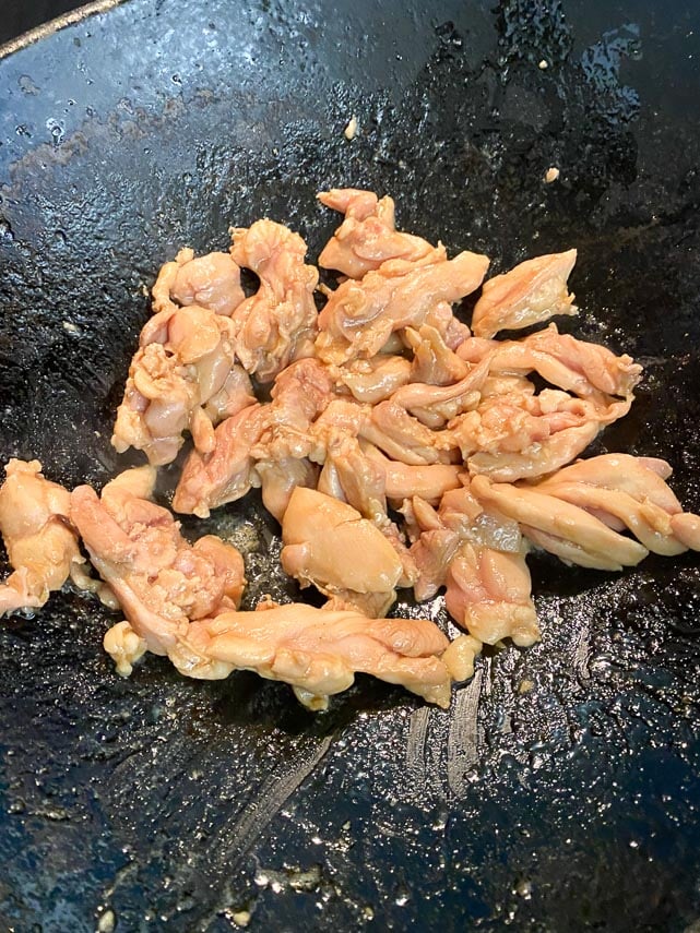 stir frying chicken in a cast iron wok