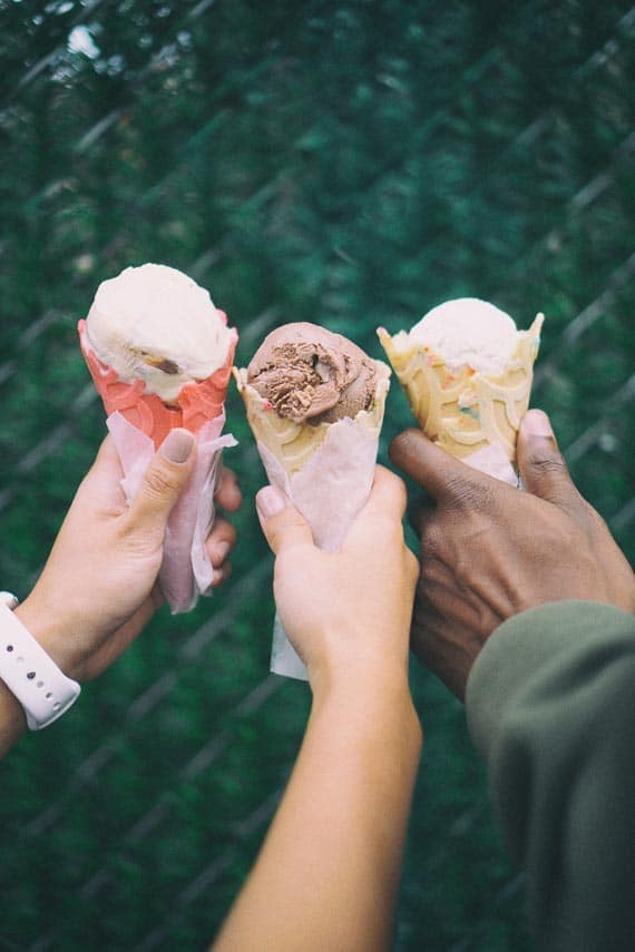 3 hands holding ice cream cones outdoors