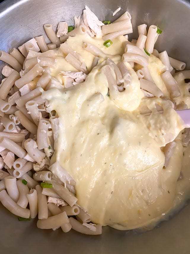 folding cheese sauce into cooked pasta for mac n cheese