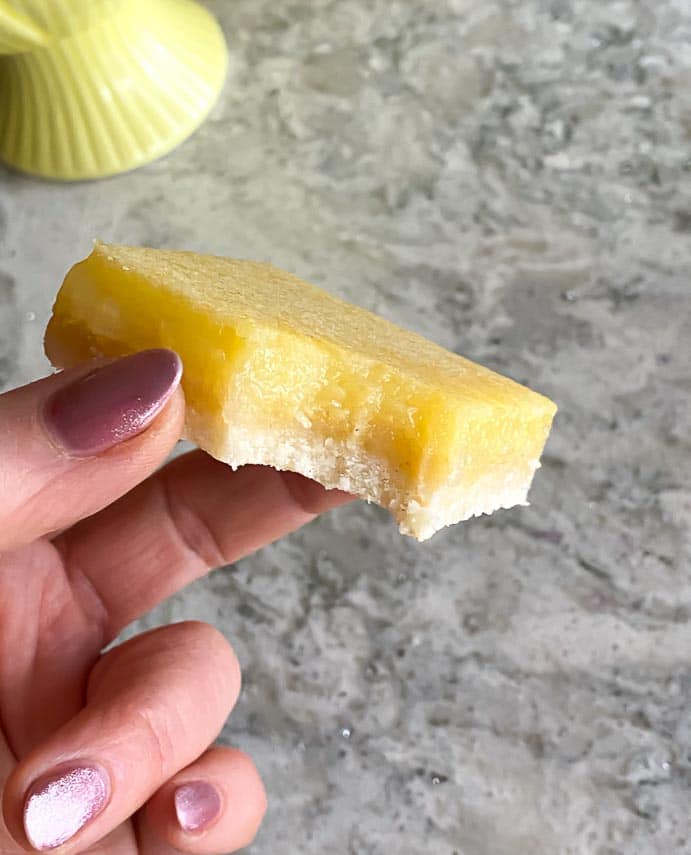 lemon bar held in hand with bite taken out
