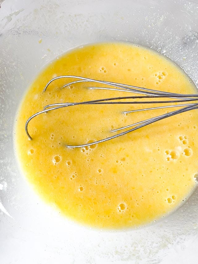 lemon juice, sugar and eggs whisked together in glass bowl, with whisk in bowl