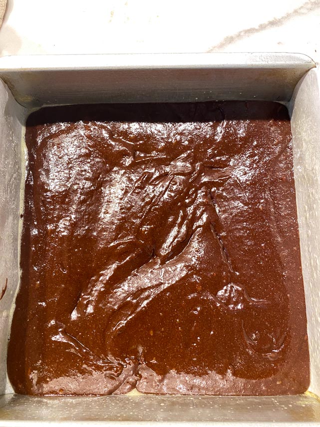 brownie batter spread in square pan, unbaked