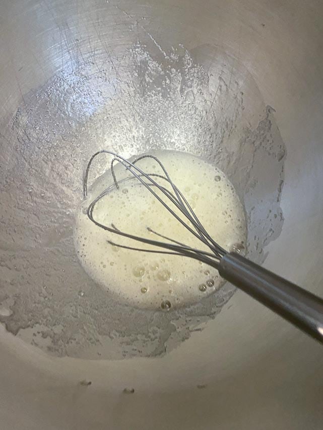 combining egg whites, sugar and cream of tartar in bowl using whisk