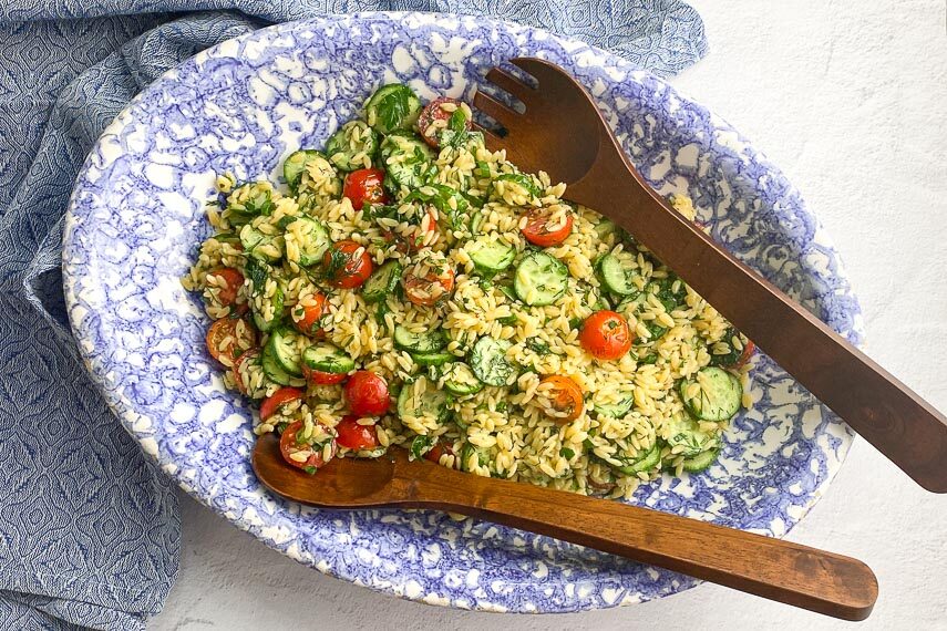 horizontal image of Low FODMAP Orzo Pasta Salad in blue and white oval bowl