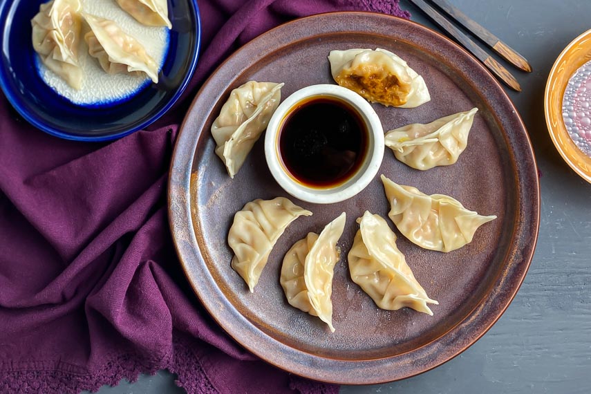 low FODMAP Pork Dumplings on brown plate with dipping sauce in white bowl 2