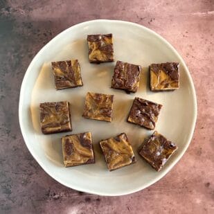 main image of espresso cream cheese brownies on light plate and brown background