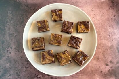 main image of espresso cream cheese brownies on light plate and brown background