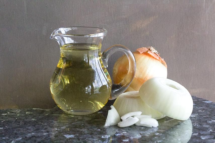 pitcher of oil and raw onions on table