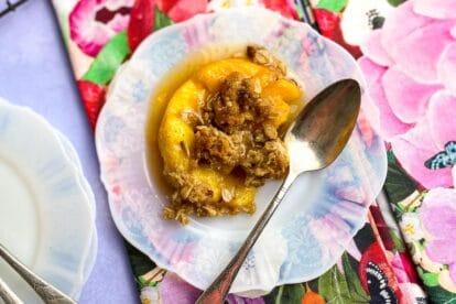 Close Up of Low FODMAP peach crisp on white plate with floral napkins and silver spoons