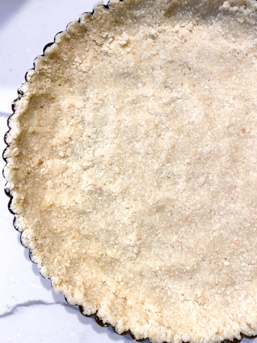 almond crust pressed into tart pan in even layer