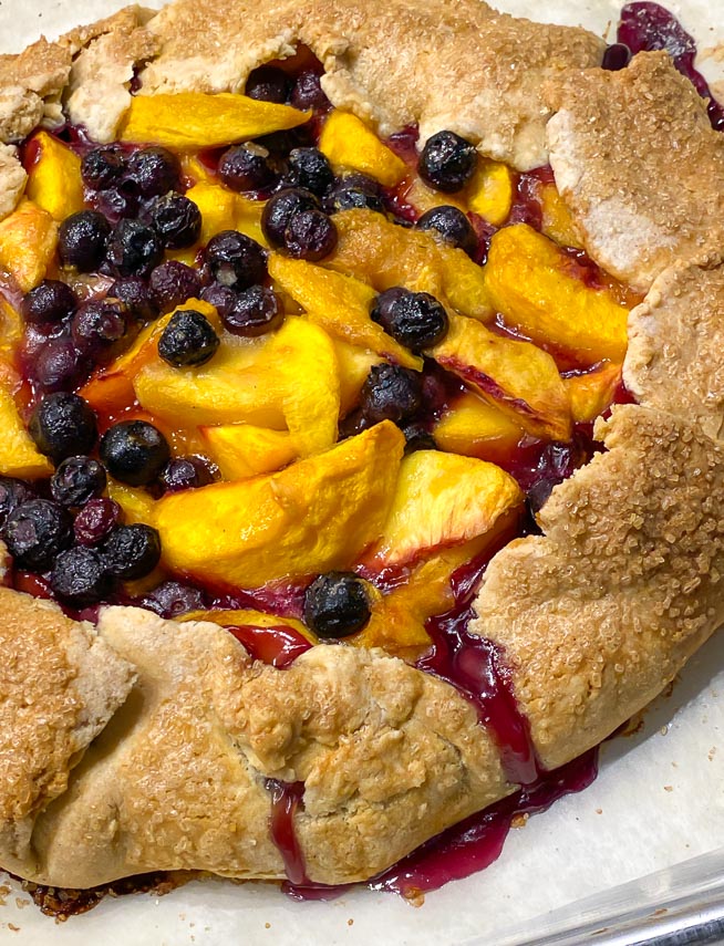 close up of baked peach blueberry crostata on pan