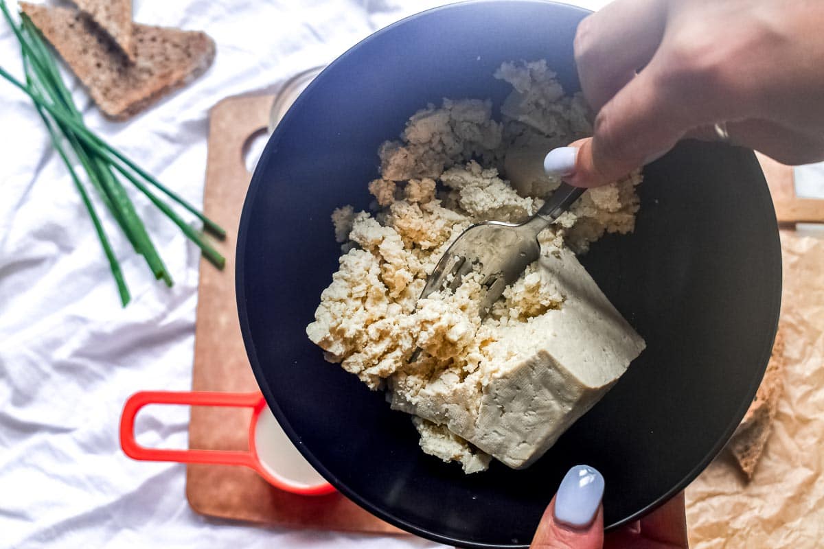 mashing tofu in bowl with fork
