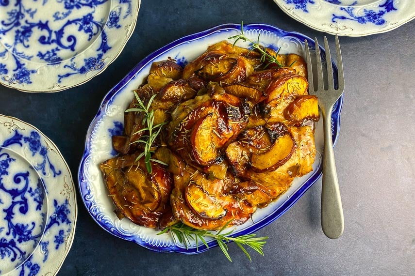 overhead image of Low FODMAP Balsamic Chicken with peaches and rosemary on decorative blue and white oval platter
